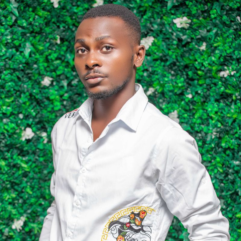 Potrait LAFON George N - SafePlace Internation A man in a white button-up shirt stands in front of a leafy green backdrop, looking directly at the camera. SafePlace International